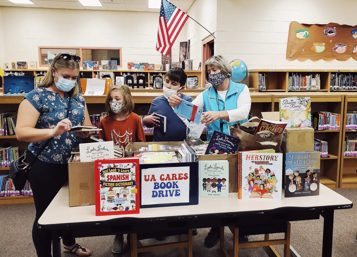 UA Cares Ambassador, Danielle Oxnam delivers books to a local elementary after hosting a book drive in her department.